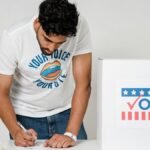 Man filling out ballot at polling station with a focus on civic duty and electoral participation.