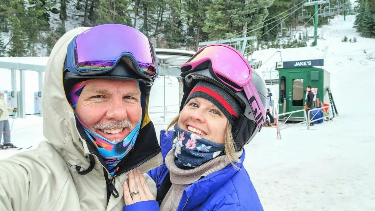 A happy couple in ski gear poses at Sundance Resort ski lift, Utah.