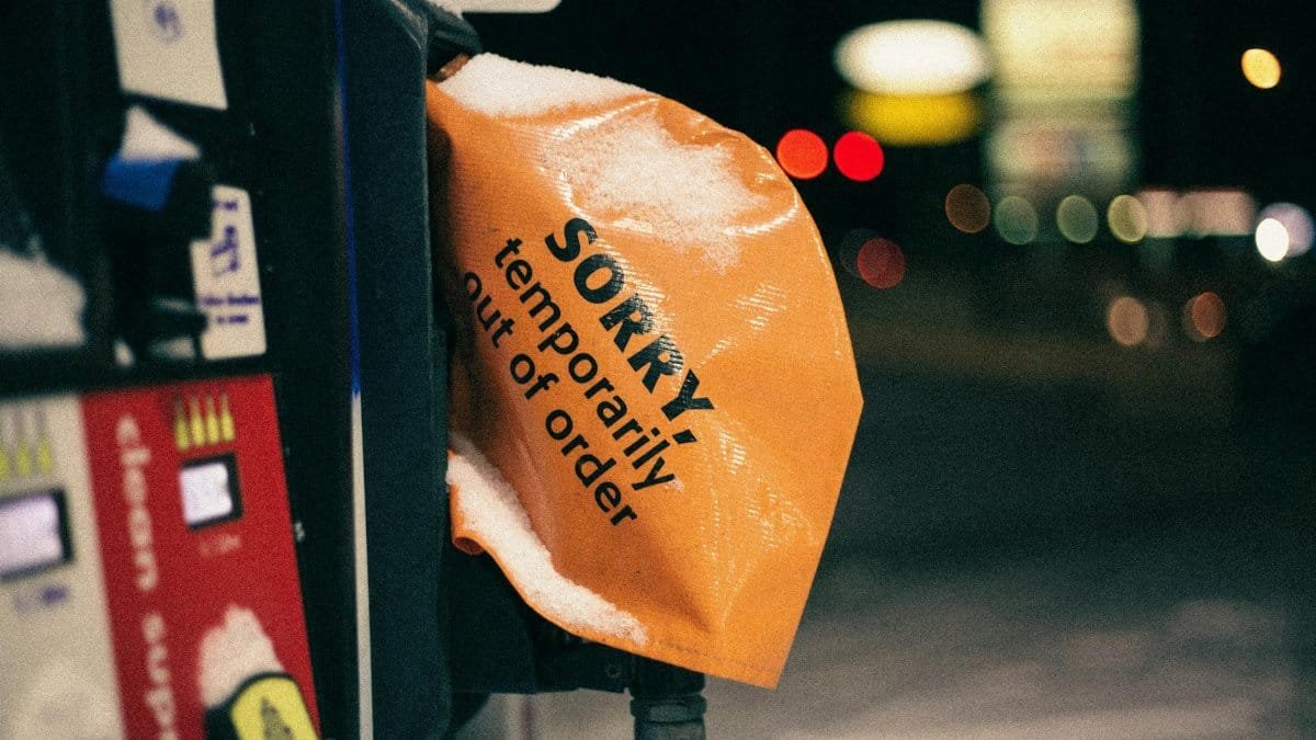 A covered fuel pump in winter with a 'temporarily out of order' sign at night.