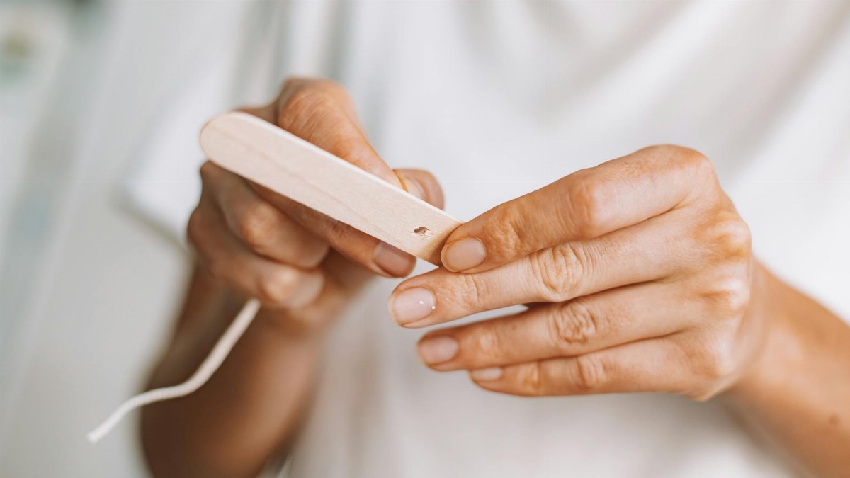 Detailed view of hands crafting with a wooden stick and string.