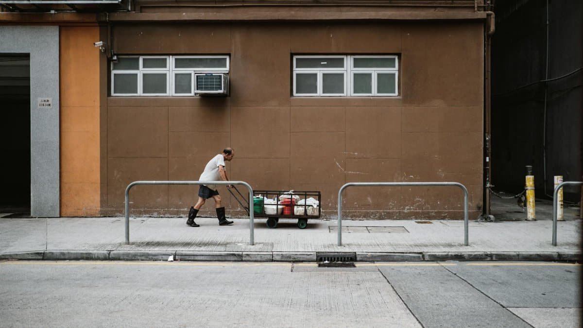 A man pulling a cart along a city street in Hong Kong, showcasing urban life and manual labor.