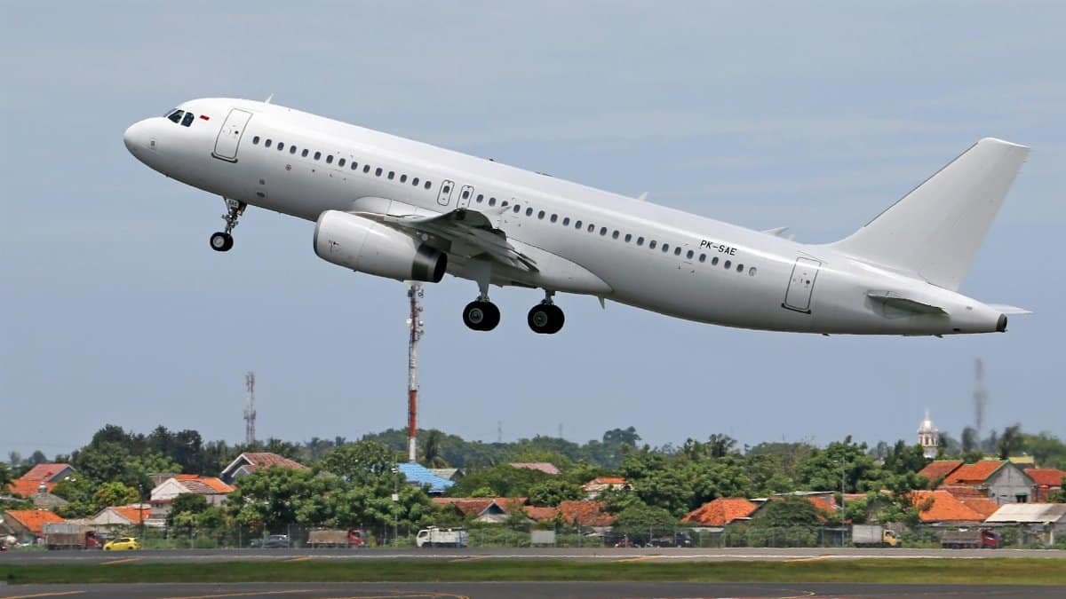 A commercial airplane lifts off from the runway, showcasing urban and rural backgrounds.