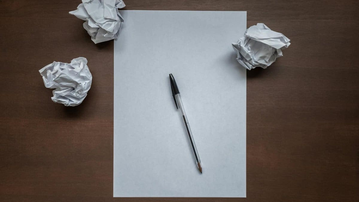Crumpled paper and pen on desk, symbolizing writer's block or creativity struggles.