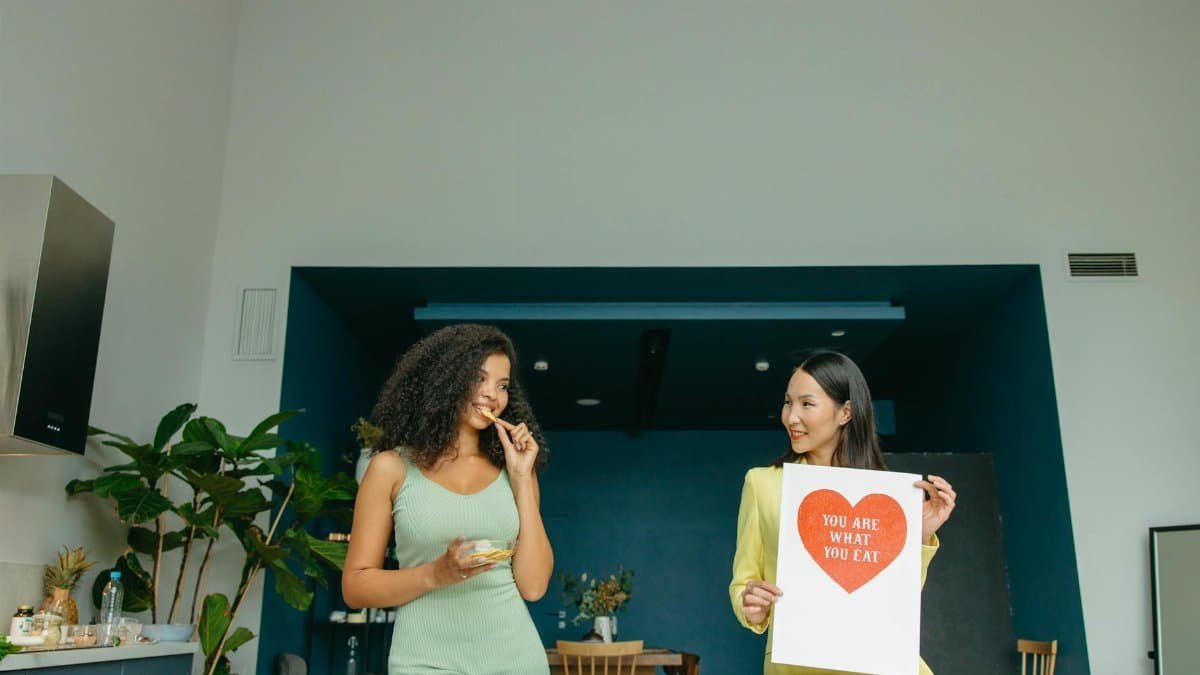 Two women enjoying healthy food and promoting nutrition awareness in a modern kitchen.