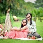 A joyful mother and daughter enjoy a picnic setting in a vibrant green garden.