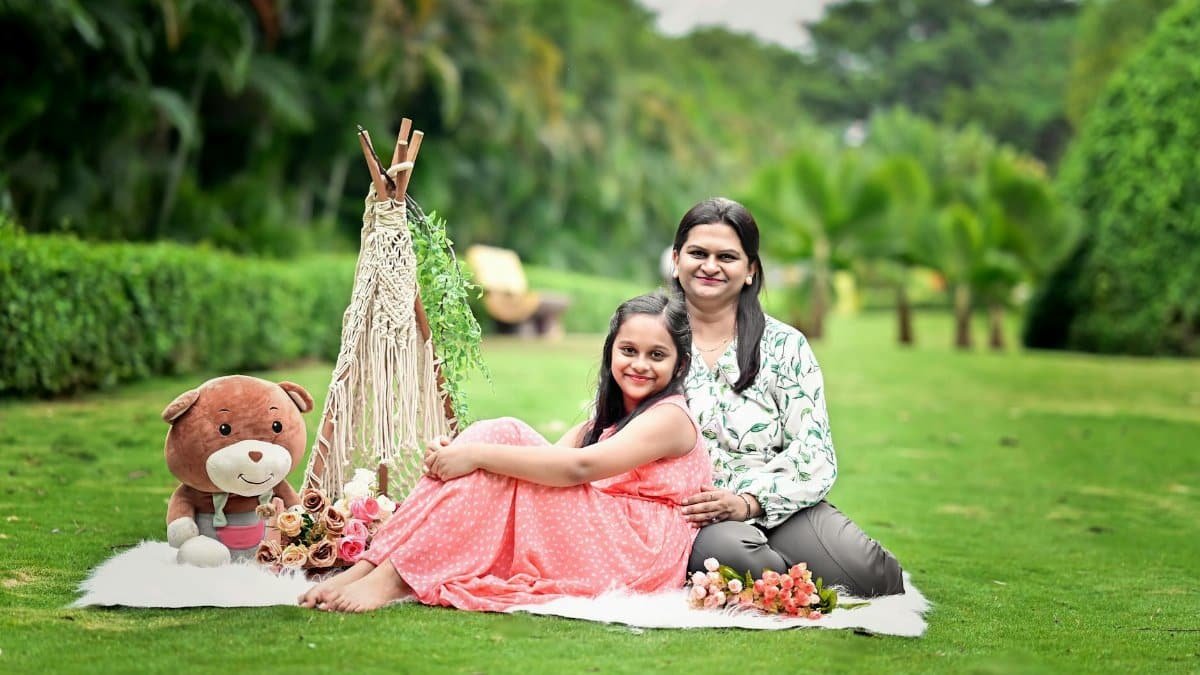 A joyful mother and daughter enjoy a picnic setting in a vibrant green garden.
