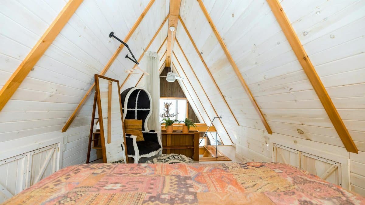 Warm attic bedroom in Stowe, Vermont with wooden beams and rustic decor.