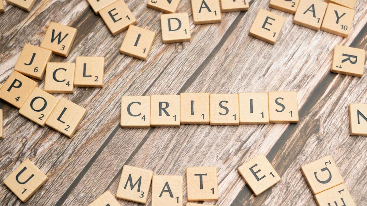 Wooden letter tiles spelling 'Crisis' on a wooden background, conveying a sense of challenge.