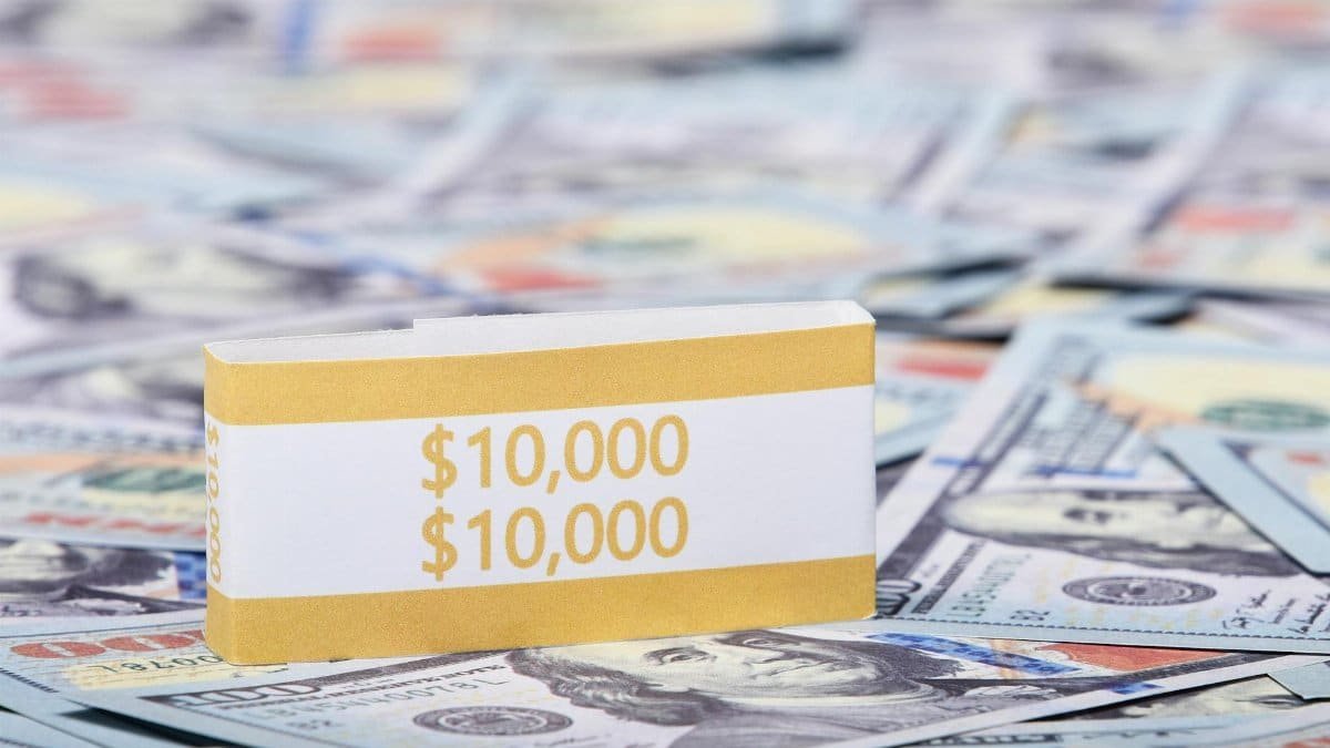 Close-up image of a stack of US dollars with a $10,000 band, symbolizing wealth and finance.