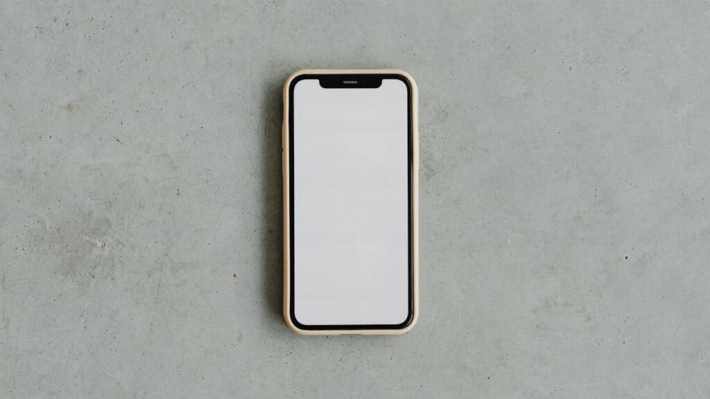 Top view of a modern smartphone with a blank white screen on a gray concrete background, ideal for mockups.