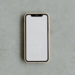 Top view of a modern smartphone with a blank white screen on a gray concrete background, ideal for mockups.