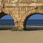 View of the ancient Roman aqueduct on the beach at Caesarea, Israel, with the sea in the background.