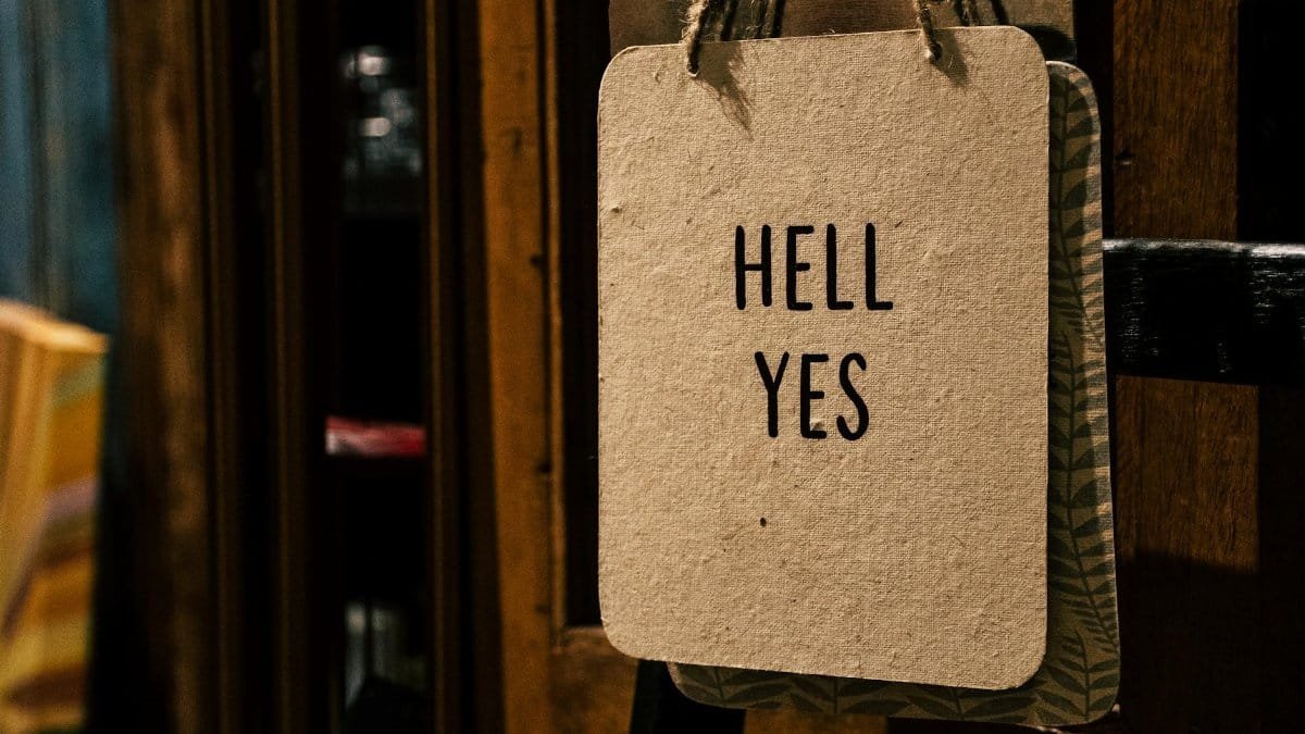 A vintage-style sign with the words 'HELL YES' hanging indoors, offering a motivational and rustic vibe.