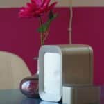Elegant interior setting featuring a sleek air purifier and vibrant pink flower in a vase on a table.