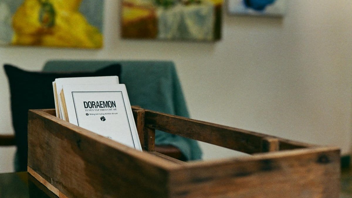 Cozy interior scene with books in a wooden box and abstract art on walls.