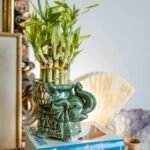 A feng shui inspired setup featuring an elephant vase, bamboo plant, books, and decorative items in a serene home decor setting.
