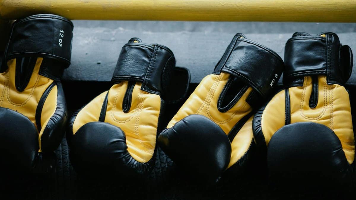 Pair of yellow and black boxing gloves resting on a gym floor.