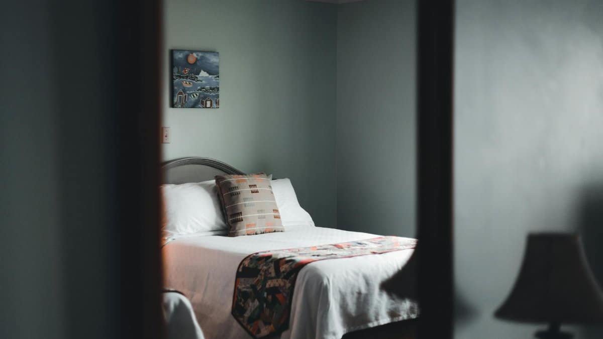 A soothing minimalist bedroom with cozy vibes, featuring a wooden bedframe and subtle decor.