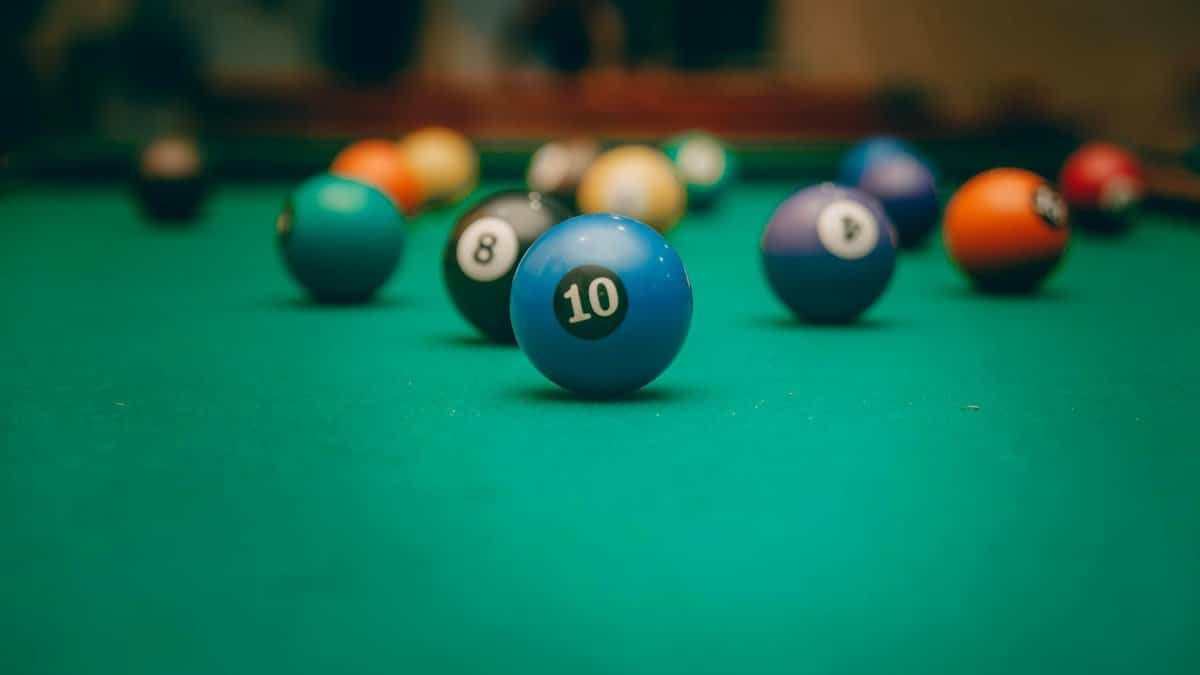 Colorful billiard balls set for a game on a green pool table indoors.