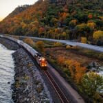 A scenic autumn train ride along a lake in Reads Landing, Minnesota, surrounded by vibrant fall foliage.
