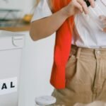 A woman sorts recyclables in an eco-friendly kitchen setup, focusing on metal and glass.