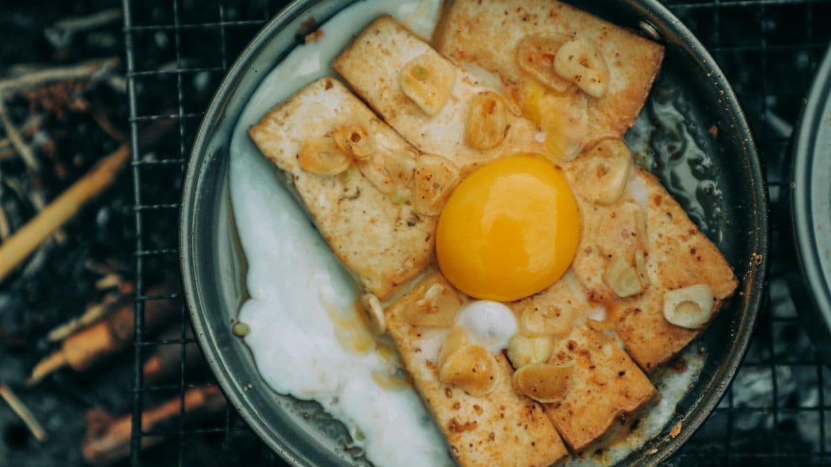 Appetizing fried egg yolk and tofu cooked with garlic in a rustic skillet.