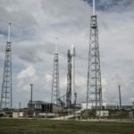 Industrial rocket launch pad with tall towers under a cloudy sky, perfect for technology and energy themes.