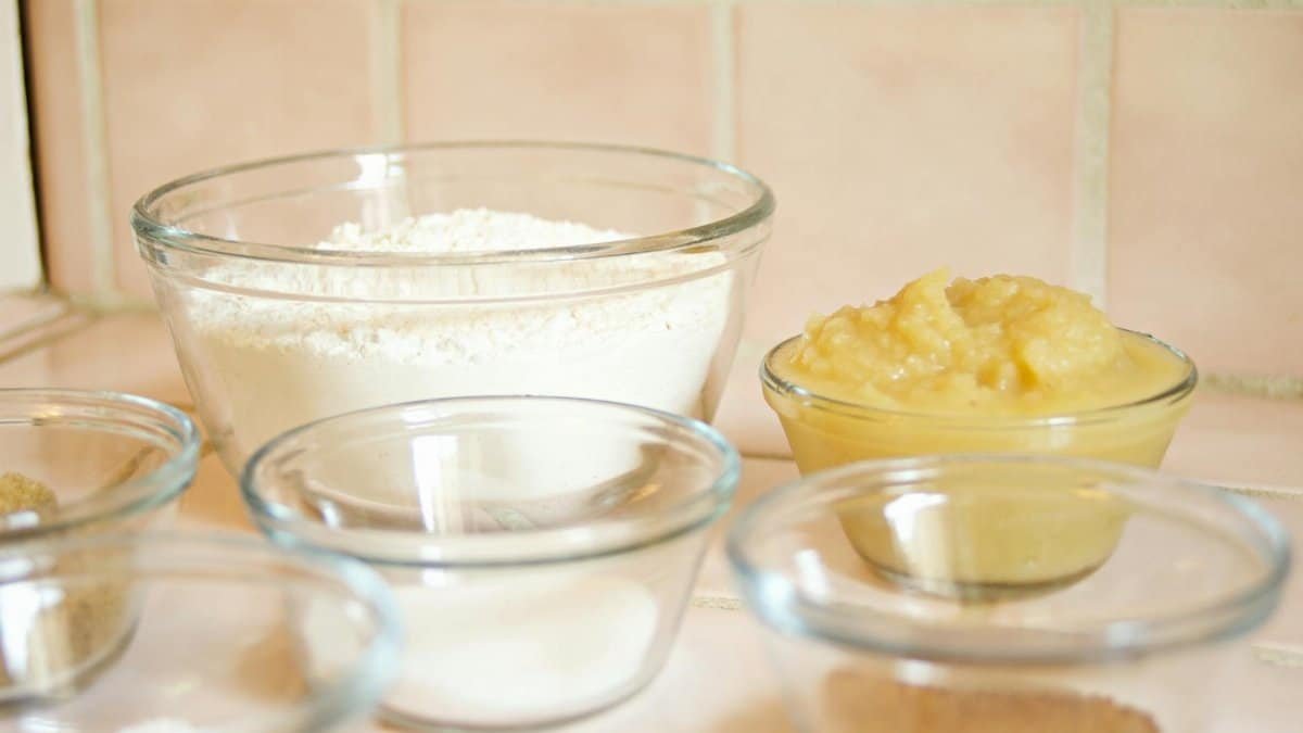 Close-up of glass bowls with flour, applesauce, and sugar, ready for baking.