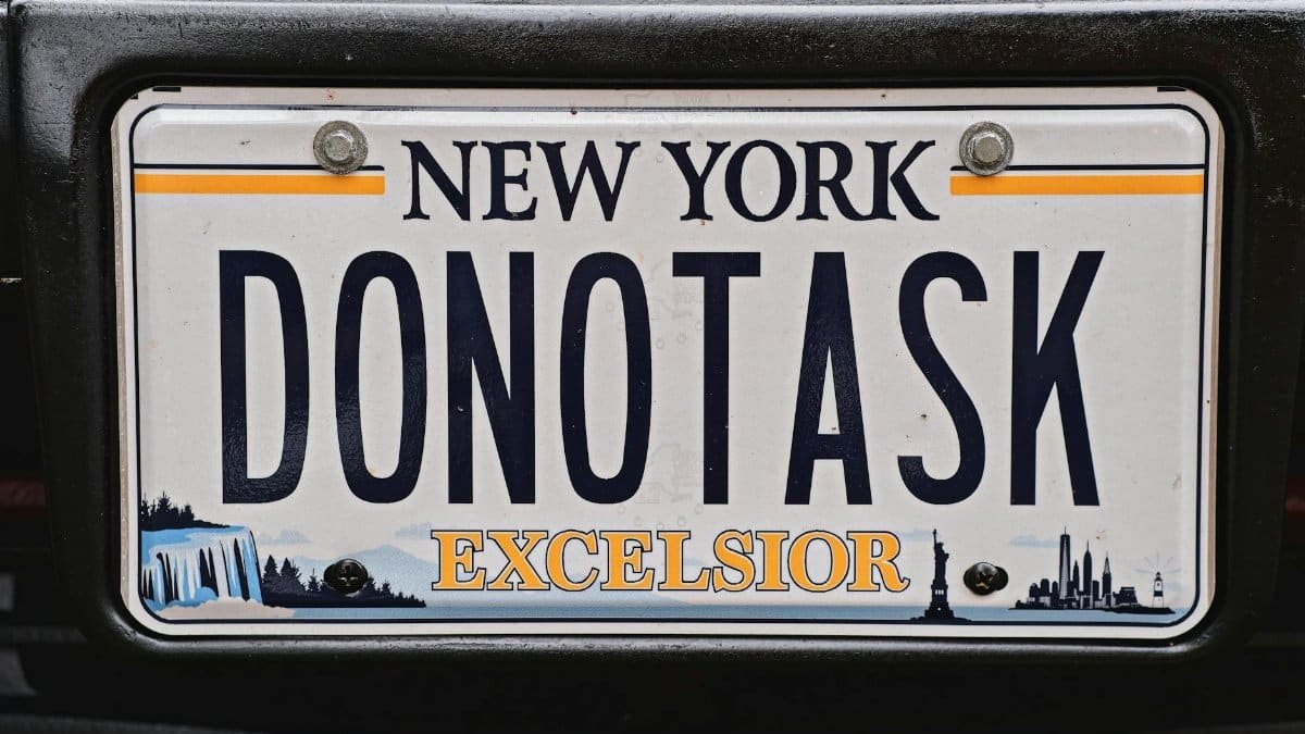 Detailed close-up of a custom New York license plate with unique lettering 'DONOTASK'.