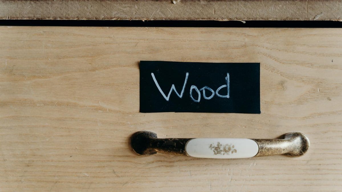 Detailed view of a wooden cabinet drawer with chalk-labeled sign and vintage handle.