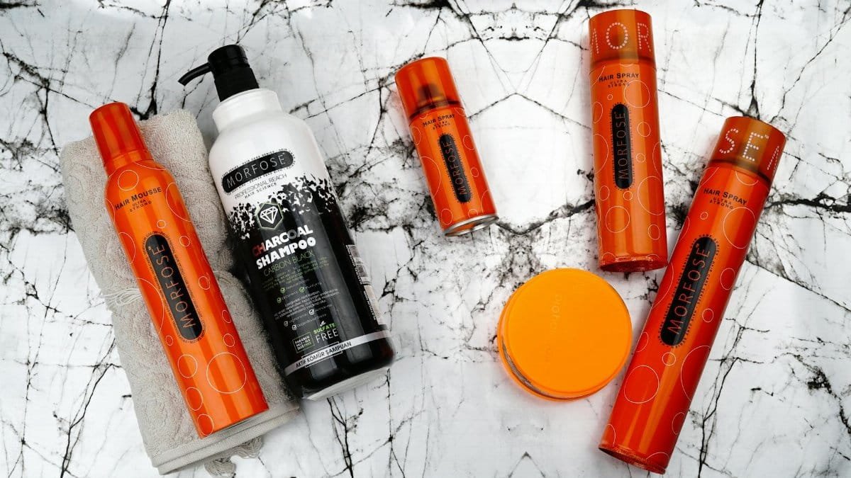 Flat lay of Morfose hair care products including mousse and charcoal shampoo on marble.