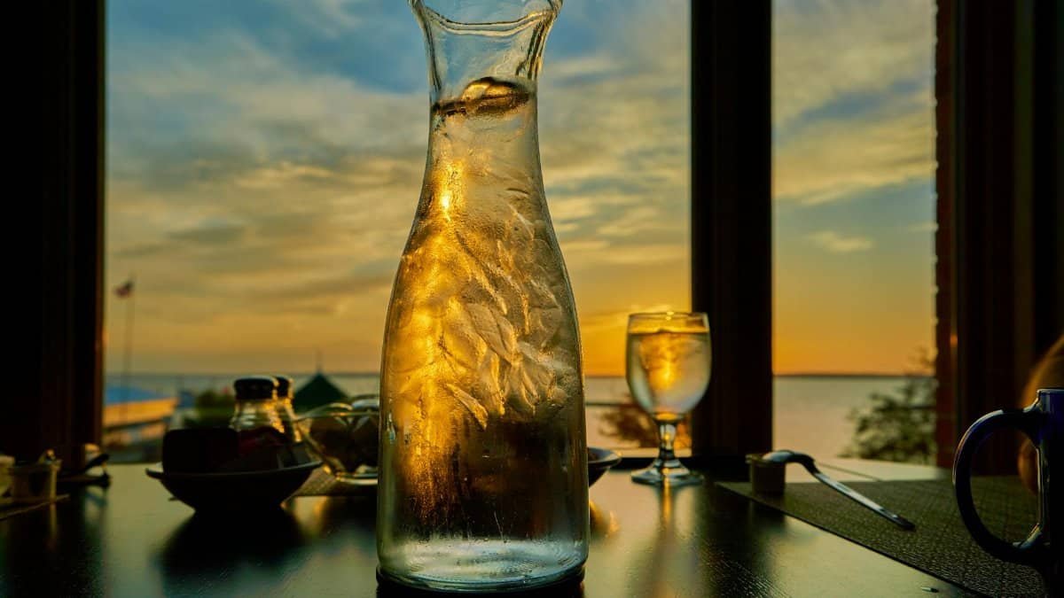 Glass bottle and table setting with sunset view over water from Bayfield, WI.