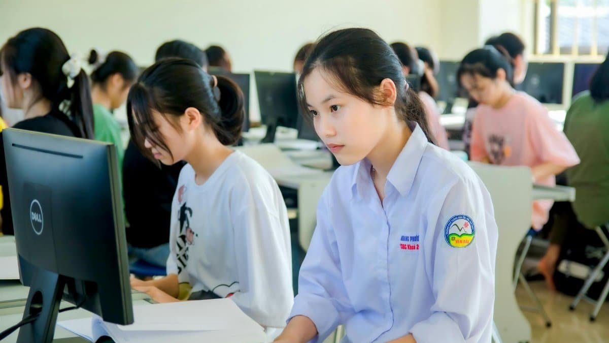 A group of students focused on computer screens in a modern classroom setting.
