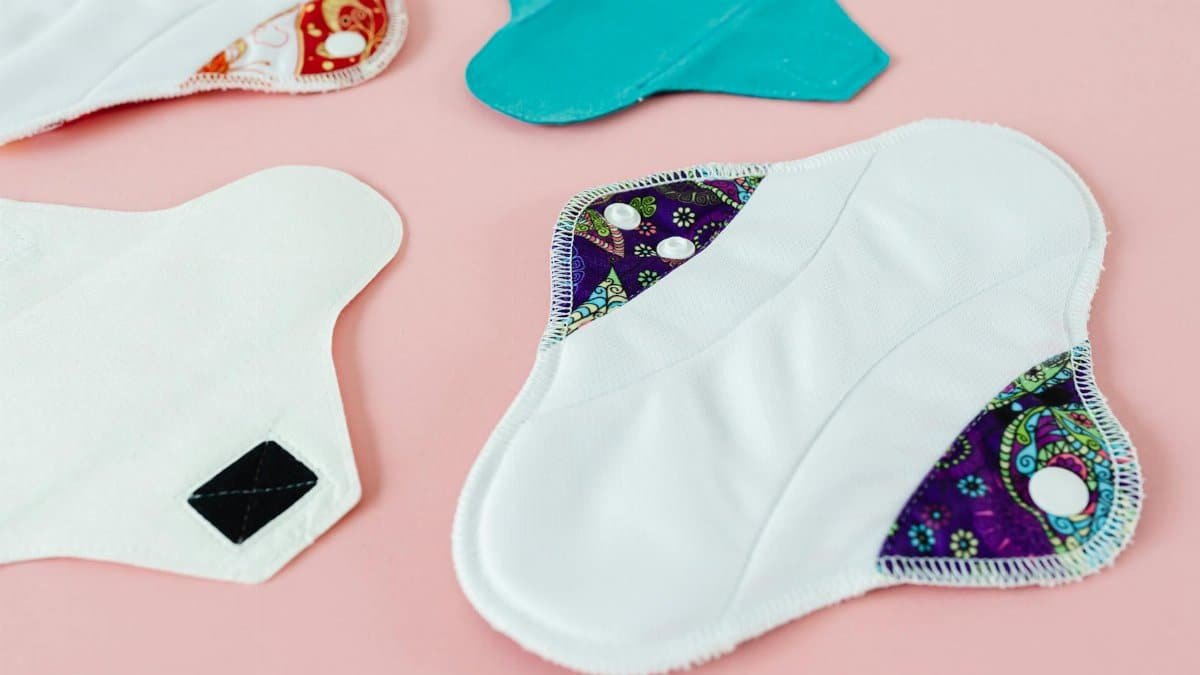 Close-up of colorful reusable menstrual pads on a pink surface, promoting eco-friendly menstruation solutions.