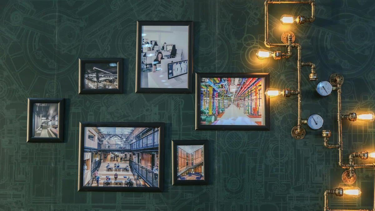 Industrial style wall art with vintage pipe lighting on a green textured wall adds a unique touch.