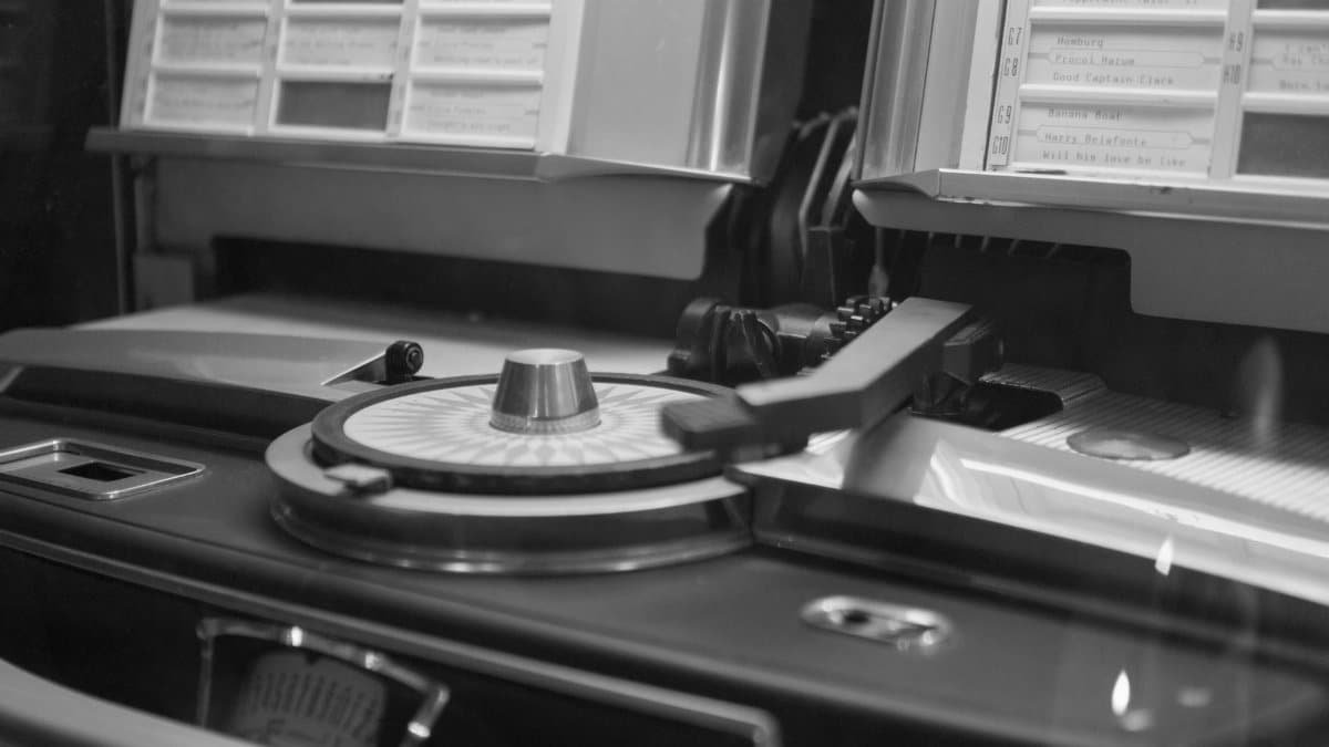 Black and white close-up of a vintage jukebox turntable with song list.