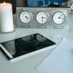 Modern office desk with candle and clocks reflecting light for a peaceful ambiance.