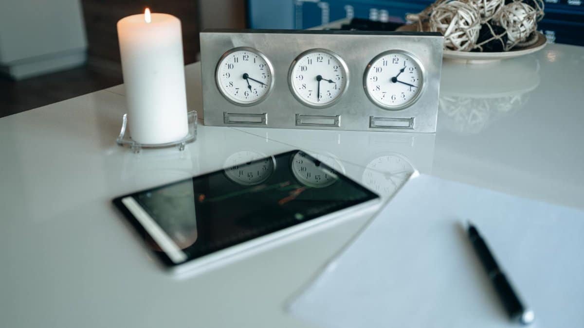 Modern office desk with candle and clocks reflecting light for a peaceful ambiance.