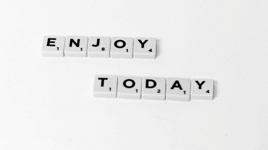 Close-up of letter tiles spelling 'Enjoy Today' on a white background, conveying positivity.