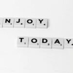 Close-up of letter tiles spelling 'Enjoy Today' on a white background, conveying positivity.