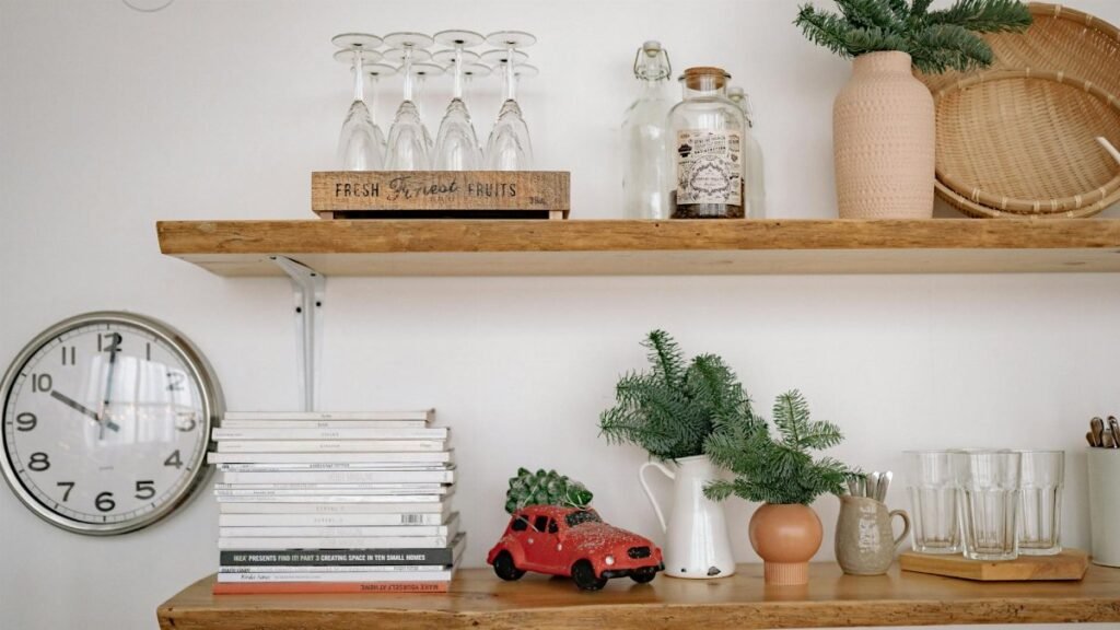 Stylish rustic shelves with books, greenery, a clock, and wine glasses for home décor inspiration.