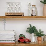 Stylish rustic shelves with books, greenery, a clock, and wine glasses for home décor inspiration.