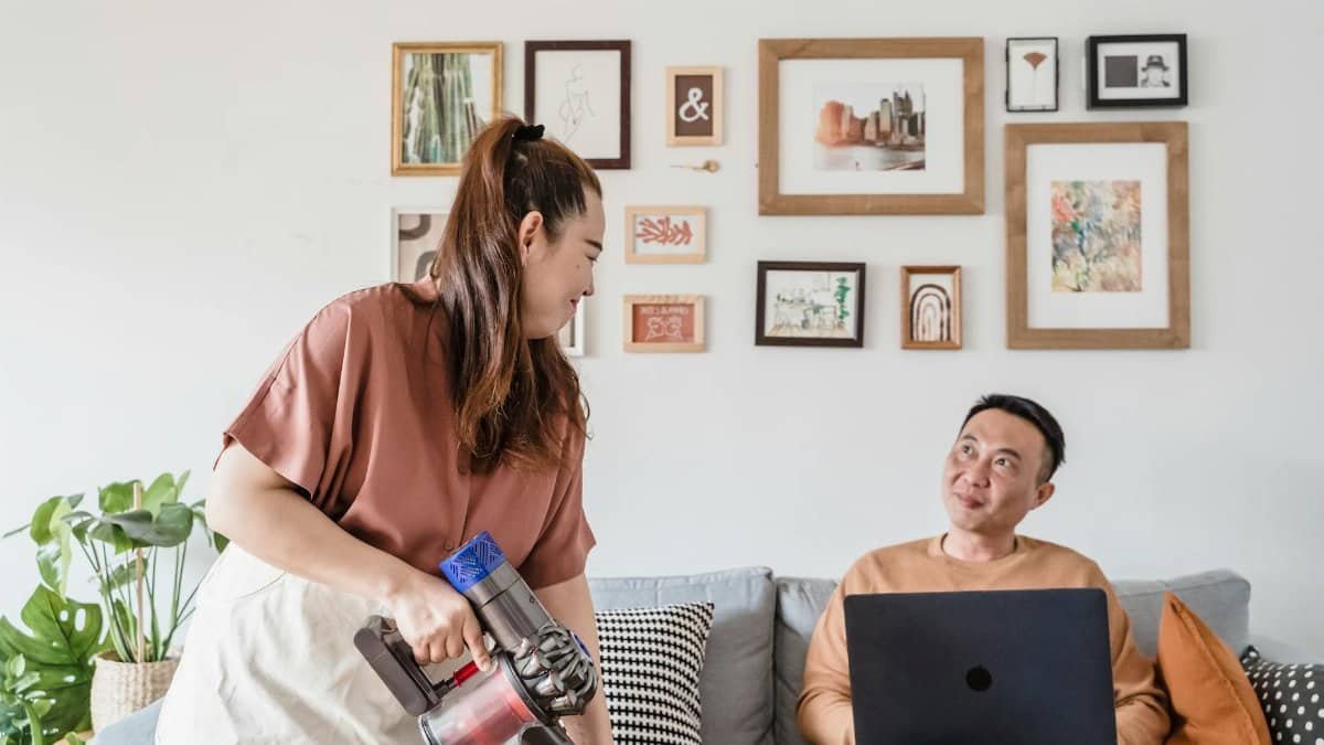 Couple enjoys cleaning the living room together with smiles and mutual support.