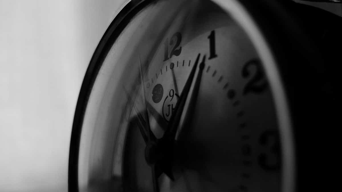 Monochrome close-up of a vintage analog clock face highlighting time passage.