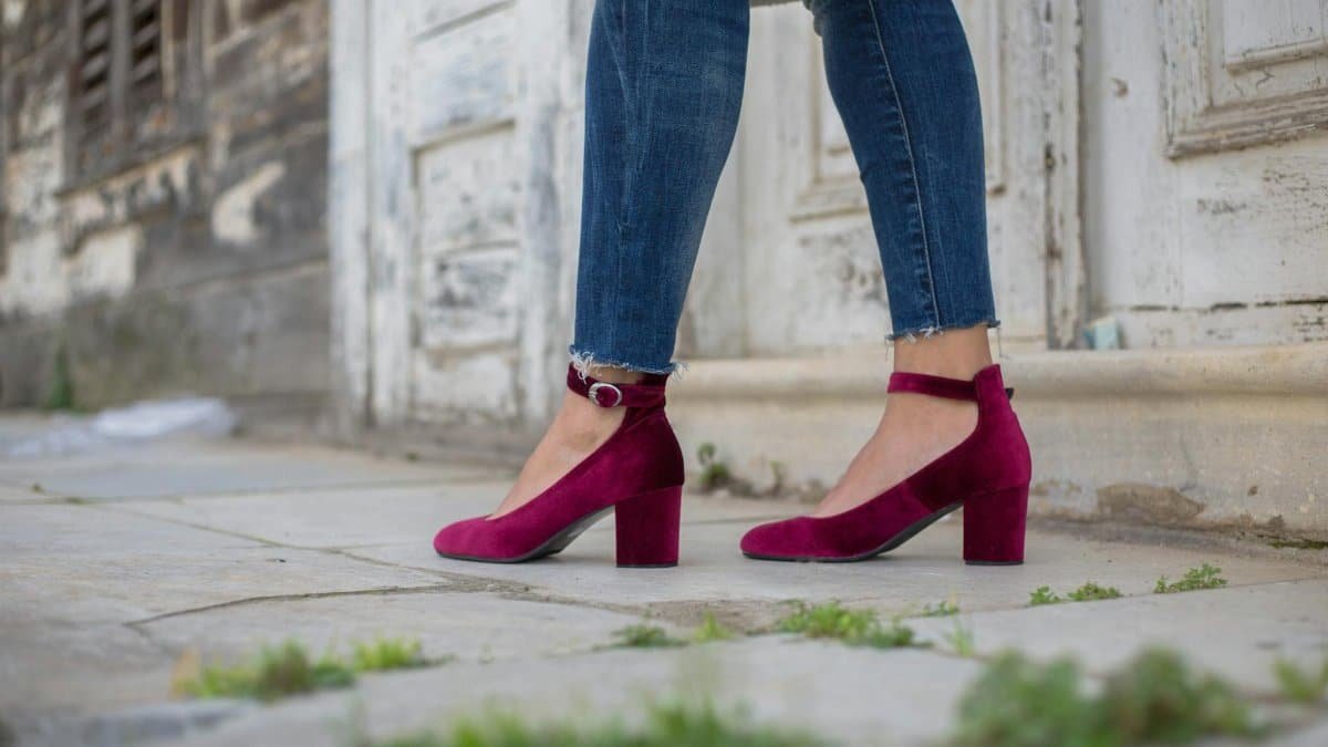 Fashionable purple ankle strap heels paired with jeans in an outdoor setting.