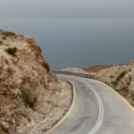 Curved mountain road leading to the Dead Sea under an overcast sky in South District, Israel.