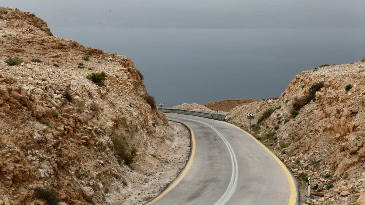 Curved mountain road leading to the Dead Sea under an overcast sky in South District, Israel.