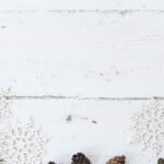 Simple holiday arrangement with snowflakes and pine cones on a white wooden background.