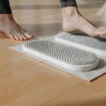 Close-up of a person using acupressure mats on a wooden floor, promoting relaxation and health.
