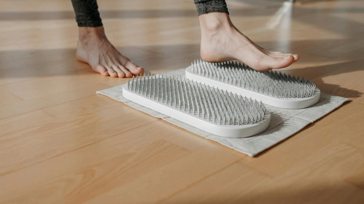 Close-up of a person using acupressure mats on a wooden floor, promoting relaxation and health.